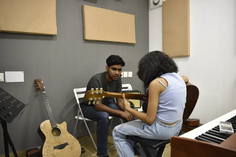 A guitar lesson at Prism, with a keyboard beside the student
